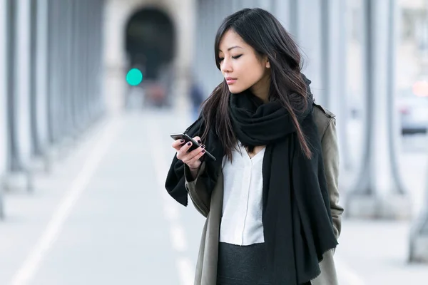 Concentrato asiatico giovane donna utilizzando il suo cellulare in the street . — Foto Stock