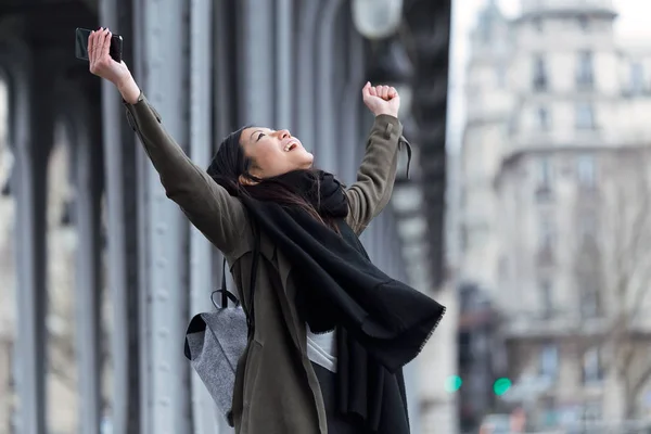 Excited asian young woman celebrating a success in the street. — Stock Photo, Image