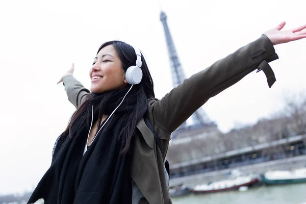 Jovem asiática excitada ouvindo música e desfrutando de um momento em frente à Torre Eiffel em Paris . — Fotografia de Stock