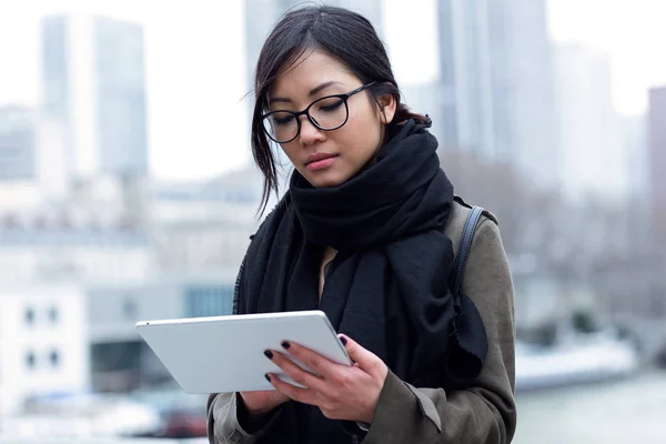 Hermosa mujer joven asiática usando su tableta digital frente al río Sena en París . — Foto de Stock