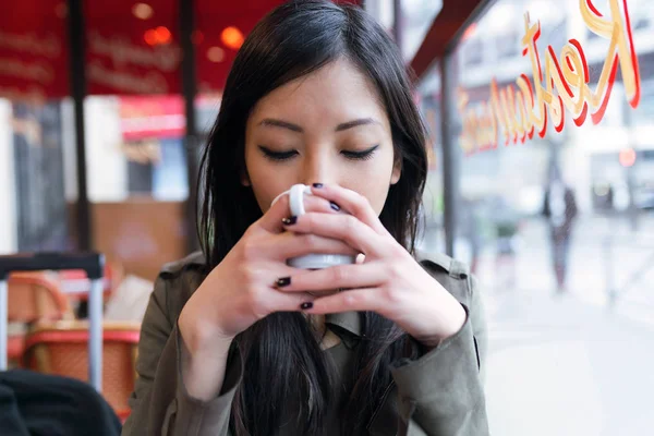 コーヒー ショップのテラスでコーヒーを飲みながら美しい若いアジア女性. — ストック写真