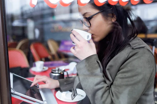 Όμορφη νεαρή γυναίκα Ασιατική χρήση της ψηφιακή ταμπλέτα πίνοντας τον καφέ στην καφετέρια. — Φωτογραφία Αρχείου