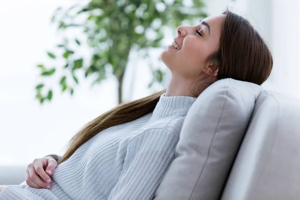 Gülümseyen genç kadın evde kanepede rahatlatıcı. — Stok fotoğraf