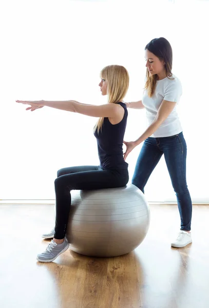 Fisioterapeuta ayudando al paciente a hacer ejercicio sobre la pelota de fitness en la sala de fisioterapia . —  Fotos de Stock