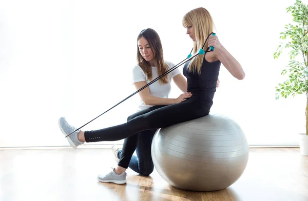 Fisioterapeuta ayudando al paciente a hacer ejercicio sobre la pelota de fitness en la sala de fisioterapia . —  Fotos de Stock