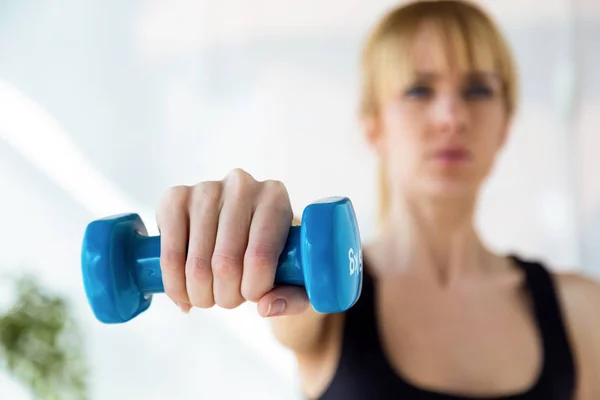 Deportiva joven haciendo ejercicio muscular con pesas azules en sala de fisioterapia . — Foto de Stock