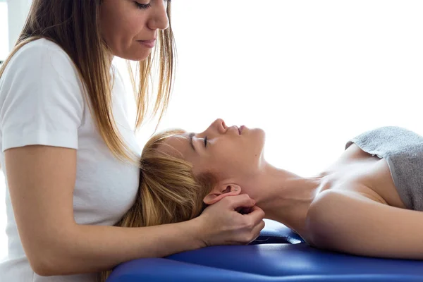 Joven fisioterapeuta haciendo un tratamiento del cuello al paciente en una sala de fisioterapia. Rehabilitación, masaje médico y concepto de terapia manual . — Foto de Stock
