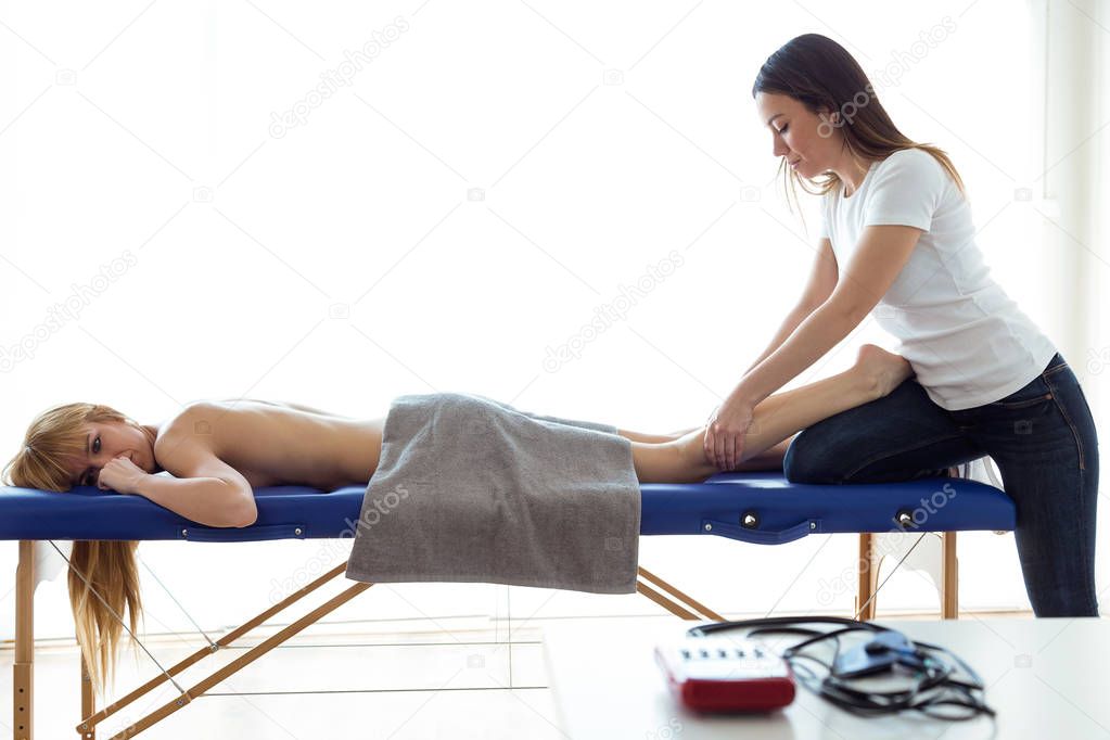 Young physiotherapist doing a legs treatment to the patient in a physiotherapy room. Rehabilitation, medical massage and manual therapy concept.
