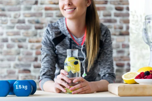 Belle jeune femme buvant du jus de citron et de baies dans la cuisine à la maison . — Photo