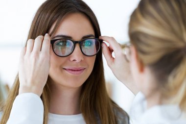 Göz doktoru ve genç ve güzel kadın gözlük optik seçme.