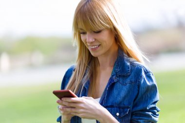 Parkta cep telefonu kullanan genç ve güzel kadın.