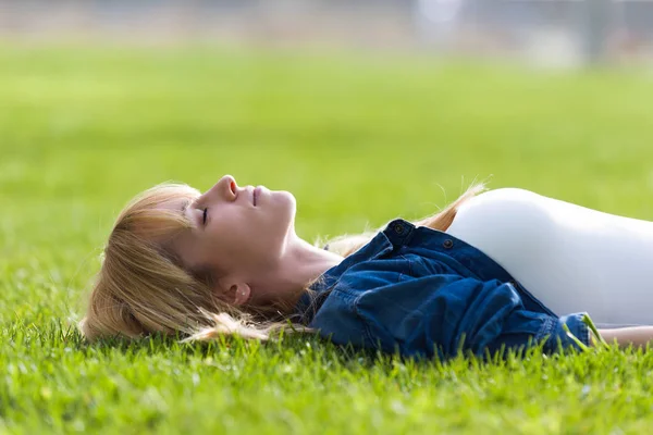 Hübsche junge Frau entspannt sich im Gras im Park. — Stockfoto