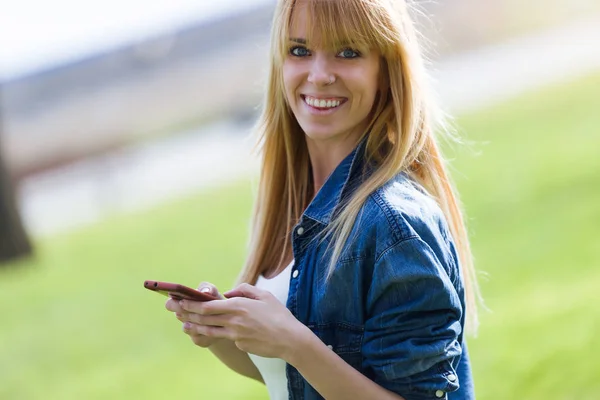 Mulher bonita usando seu telefone celular no parque . — Fotografia de Stock