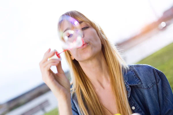 Mulher bonita se divertindo com bolhas de sabão no parque . — Fotografia de Stock
