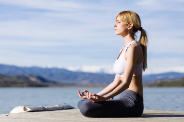 Göl yanındaki yoga yaparken zinde ve sportif genç kadın.