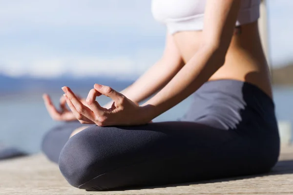 Primer plano de una joven haciendo yoga junto al lago . — Foto de Stock