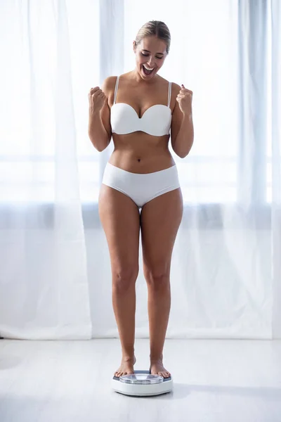 Mujer joven y saludable, feliz de ver que ha perdido peso en la escala de peso en casa . — Foto de Stock
