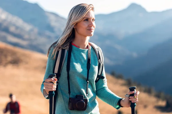 Csinos fiatal nő utazó hátizsák néz oldalra, miközben séta a hegyen. — Stock Fotó