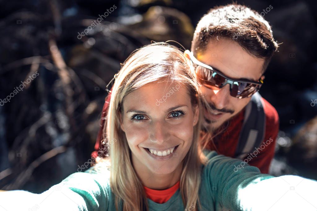 Young couple of hikers taking a selfie while standing in the forest.