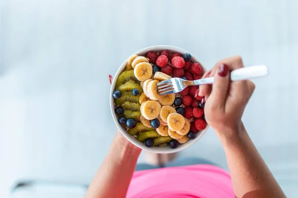 Mãos de mulher segurando uma tigela com frutas frescas enquanto está em casa . — Fotografia de Stock