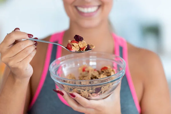 Sorrindo jovem mulher comendo cereais com morangos em casa . — Fotografia de Stock