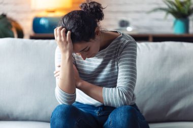 Depresyondaki genç kadın evdeki kanepede otururken sorunlarını düşünüyor..