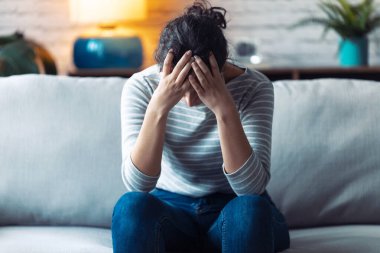 Depresyondaki genç kadın evdeki kanepede otururken sorunlarını düşünüyor..
