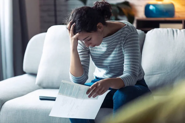 Worried young woman thinking about her problems while holding bills of home. — Stock Photo, Image
