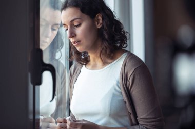 Evdeki pencereden bakarken ağlayan üzgün genç bir kadın..