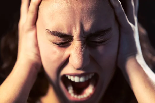 En ung kvinna i närbild skriker på svart bakgrund. Begreppet psykisk sjukdom. — Stockfoto