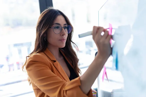 Entreprise jeune femme travaillant sur tableau blanc avec post-it autocollants dans le bureau . — Photo