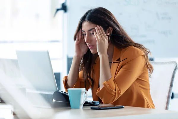 Mujer joven de negocios con dolor de cabeza trabajando con el ordenador portátil en la oficina . —  Fotos de Stock