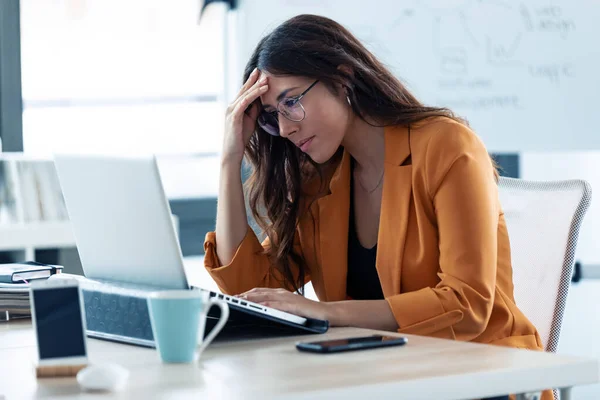 Üzleti fiatal nő fejfájással dolgozik laptop az irodában. — Stock Fotó