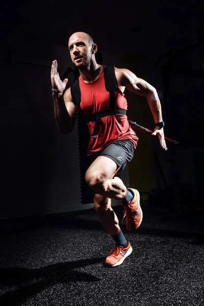 Hombre muscular durante el entrenamiento con correas de suspensión TRX en estudio oscuro . — Foto de Stock