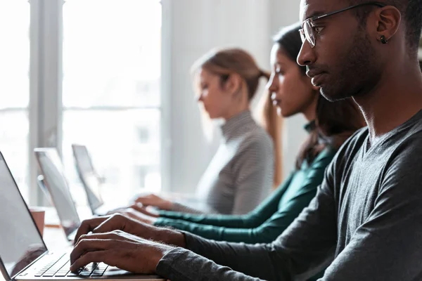 Línea de empleados concentrados que trabajan con ordenadores portátiles en el lugar de coworking . —  Fotos de Stock