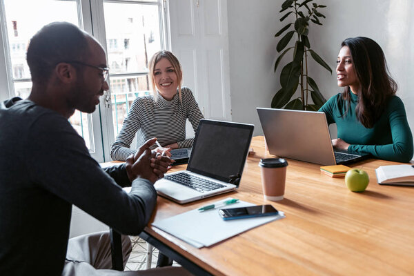 Three business colleagues working together in modern workspace. Brainstorming concept.