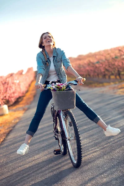 Hübsche junge Frau mit einem Oldtimer-Fahrrad genießt die Zeit im Kirschfeld im Frühling. — Stockfoto