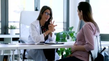 Ciddi genç jinekolog, klinikteki hamile hastasına kılavuz veriyor..