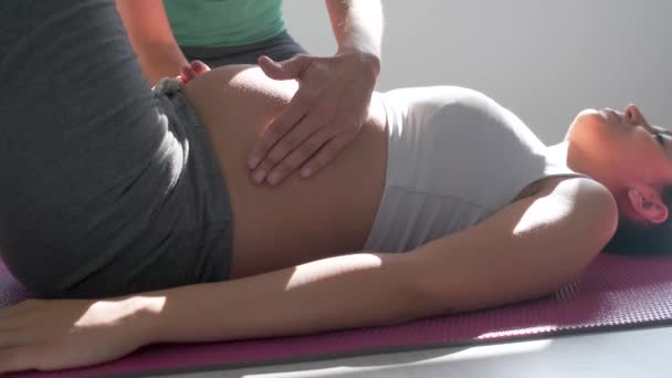 Fisioterapeuta ajudando a bela mulher grávida para fazer exercícios pilates se preparando para o parto . — Vídeo de Stock