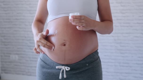 Mulher grávida aplicando creme creme loção na barriga grávida para evitar estrias . — Vídeo de Stock