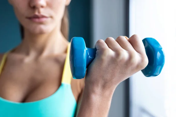 Wanita muda yang sporty melakukan latihan otot dengan dumbbells di gym . — Stok Foto