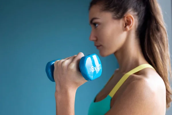 Mujer joven deportiva haciendo ejercicio muscular con pesas en el gimnasio . — Foto de Stock