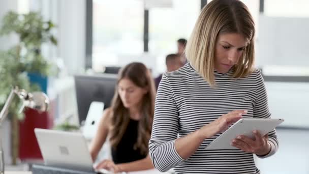 Jeune femme d'affaires souriante travaillant avec une tablette numérique et regardant la caméra dans le bureau de démarrage moderne . — Video