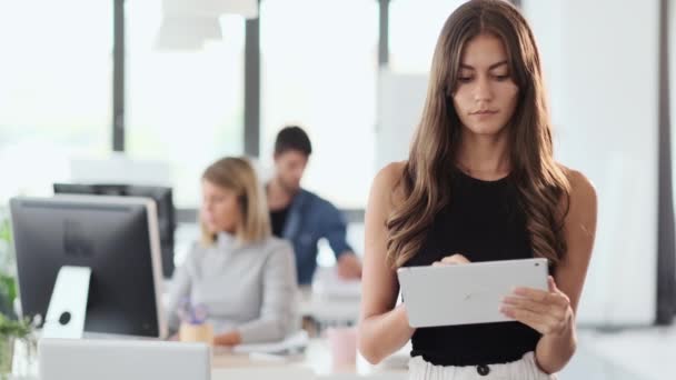 Dijital tabletle çalışan gülümseyen genç iş kadını ve modern başlangıç ofisindeki kameraya bakıyor. — Stok video