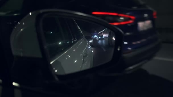 La vue de la voiture sur le rétroviseur latéral tout en conduisant à travers la ville de nuit . — Video