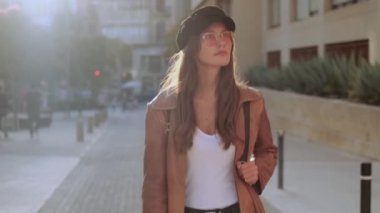 Video of pretty young woman looking the cityscape while walking in the street.