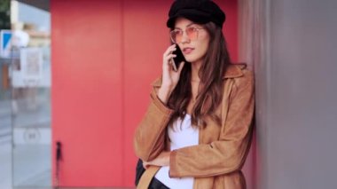 Video of pretty young woman talking on mobile phone while standing in the street.