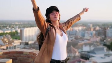 Video of pretty young woman enjoying time and sunset while standing on the rooftop.