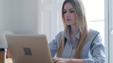 Video of concentrated young business woman working with laptop on desk in the office.