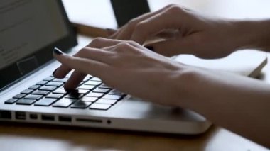 Close-up of a woman's hands using the computer keyboard in the office.